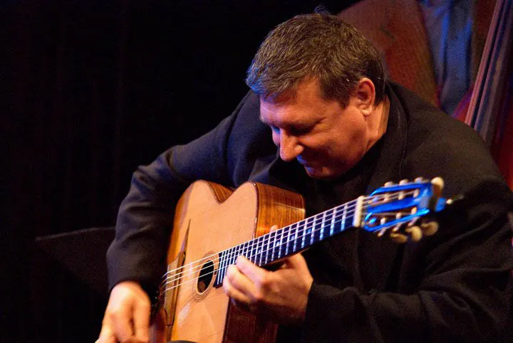 Elliot Reed onstage playing a gypsy guitar